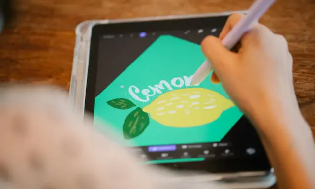 En person använder en penna för att rita en citron och texten "Cemone" i Procreate svenska på en surfplatta.