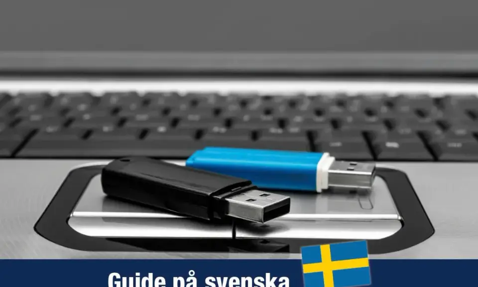 Två USB-minnen, ett svart och ett blått, ligger på ett tangentbord. En guide för Windows 11 USB på svenska.