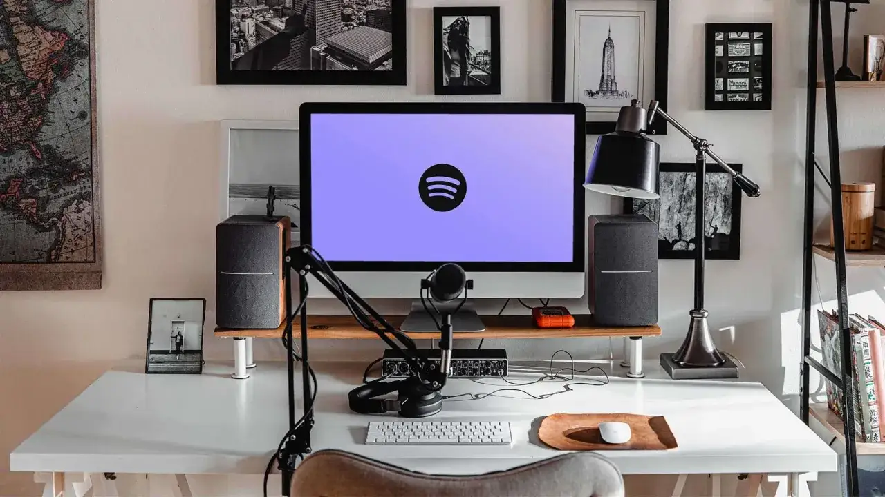 En arbetsplats redo att starta en podd. Dator med Spotify-logga, mikrofon, hörlurar och högtalare.