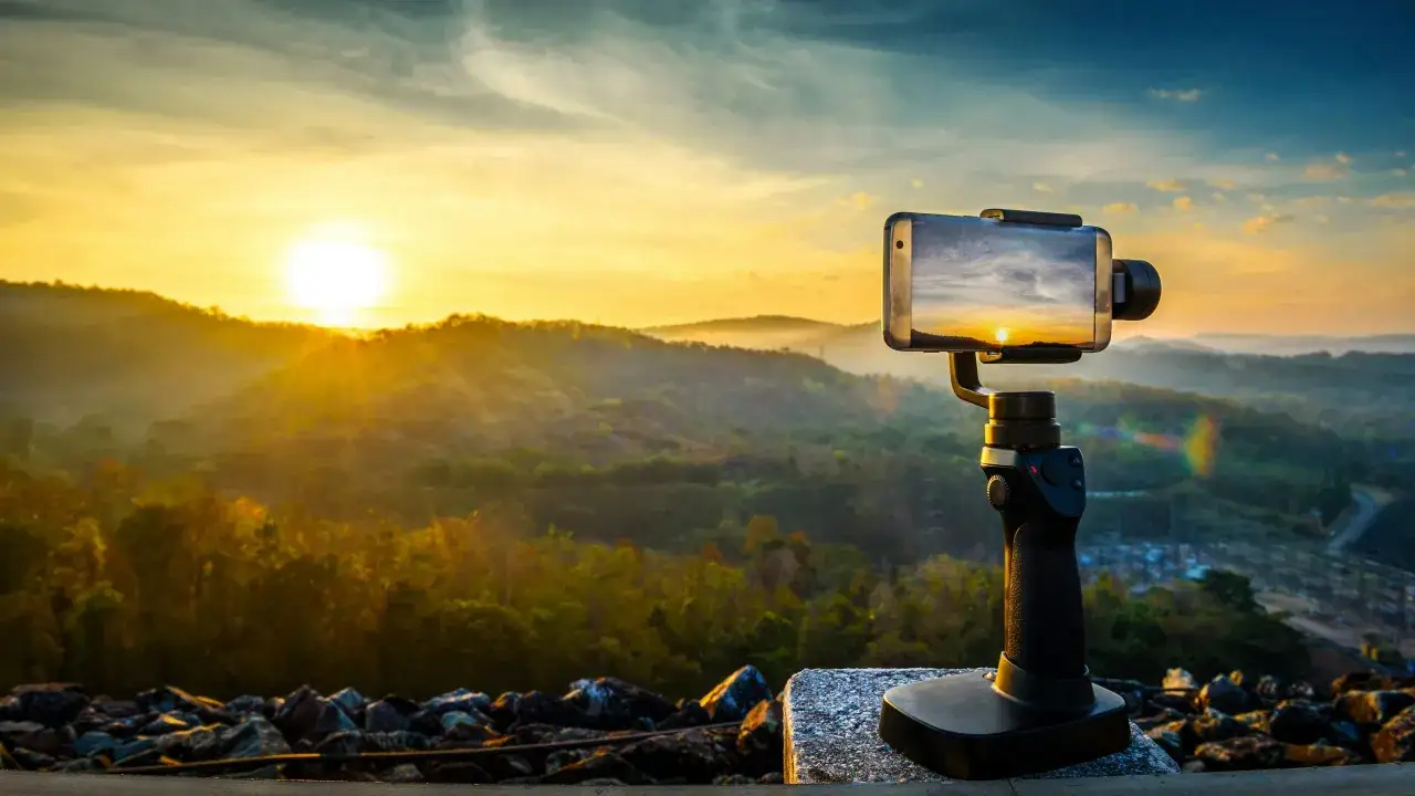 En iPhone p&aring; en gimbal f&aring;ngar en vacker soluppg&aring;ng &ouml;ver kullar. Perfekt f&ouml;r en timelapse-video.